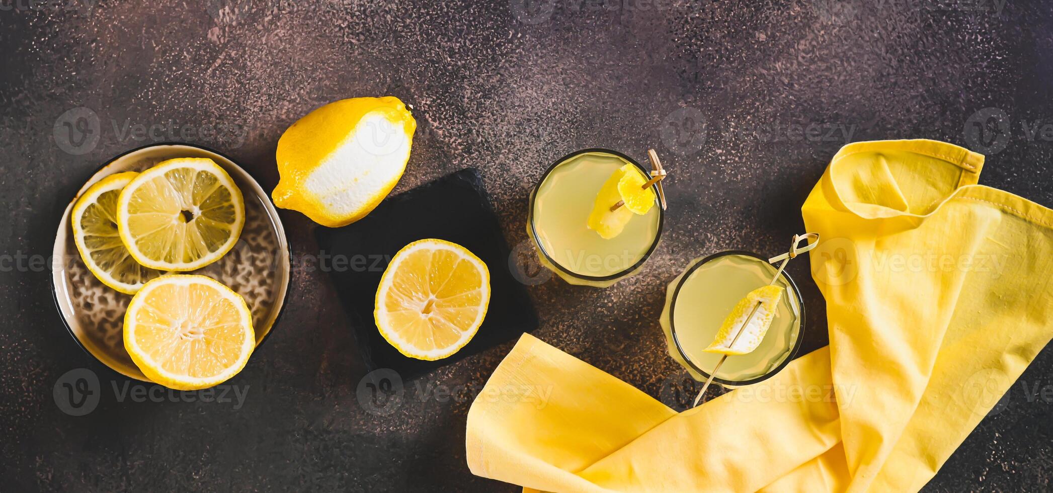 Two glasses of Italian limoncello and lemons on the table top view web banner photo