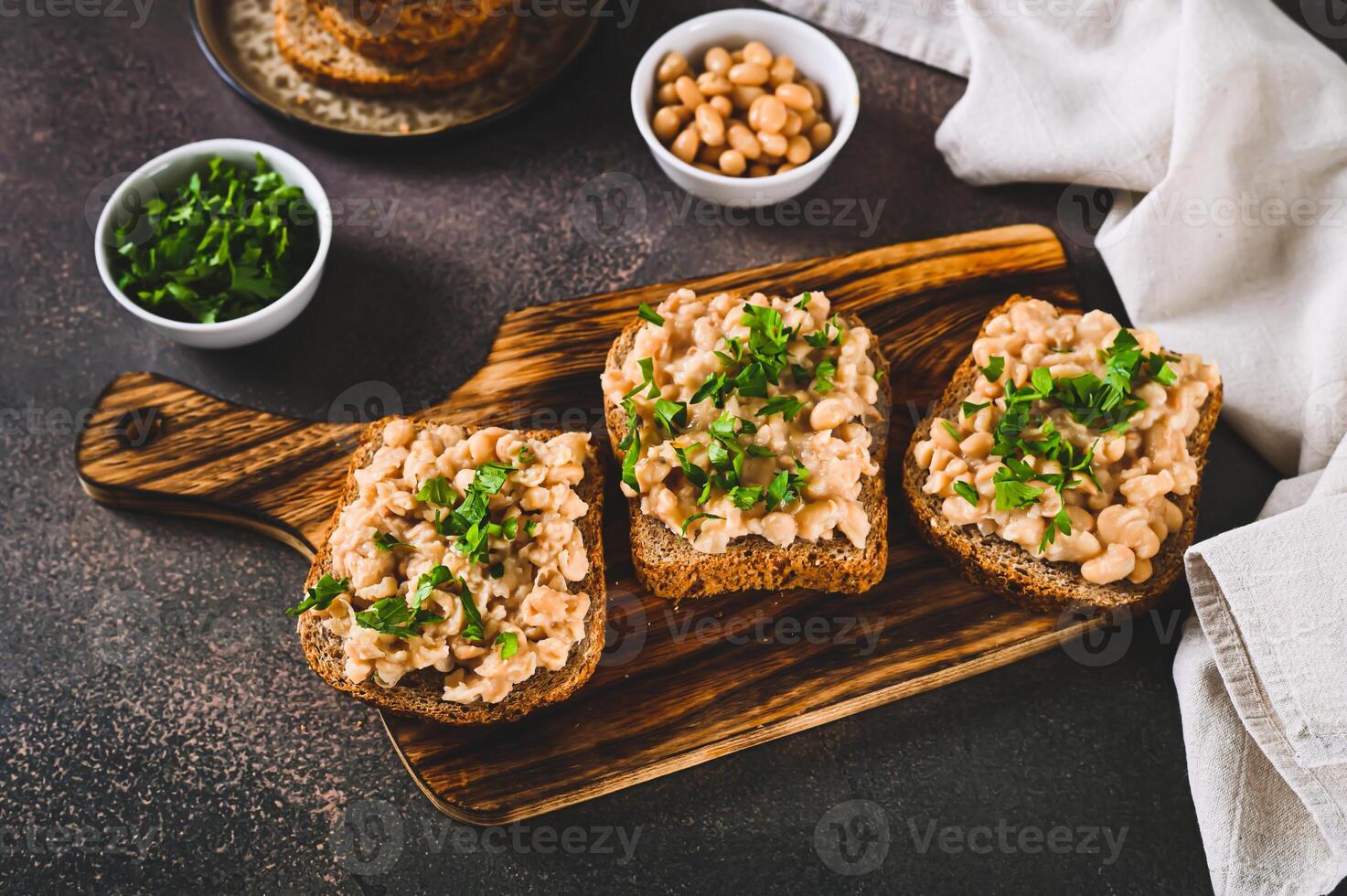 Bruschetta with mashed white beans and parsley on rye bread on a board photo