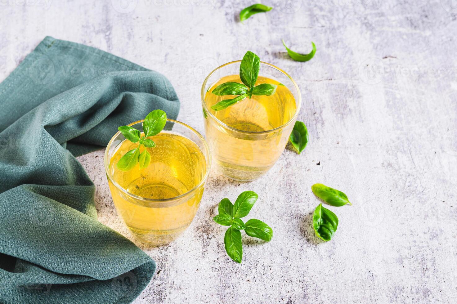 Refreshing summer basil lemonade with leaves in glasses on table photo