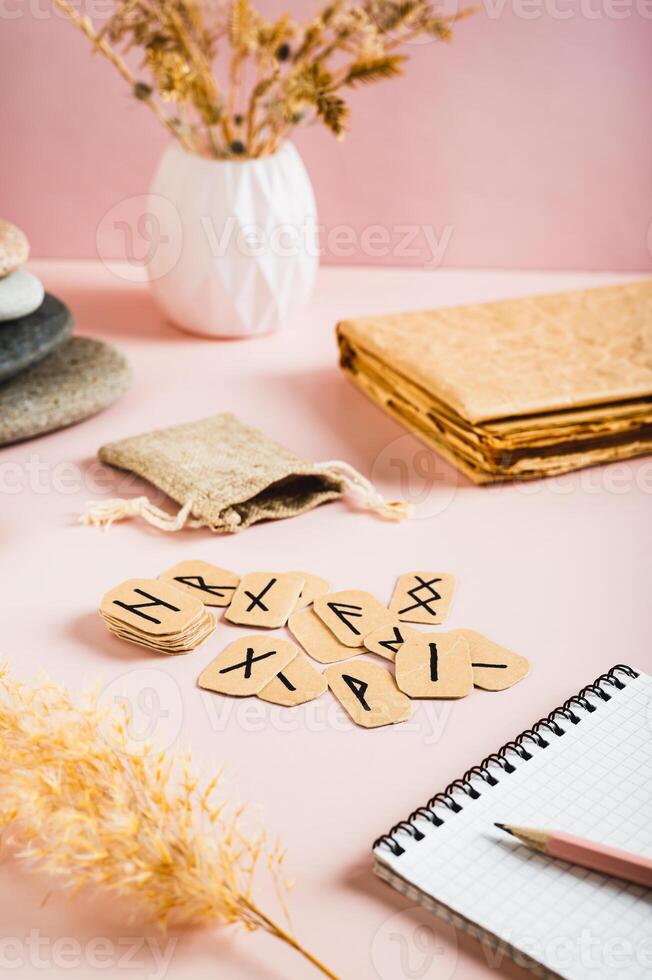 Scandinavian runes, notebook and pencil for writing on pink background vertical view photo