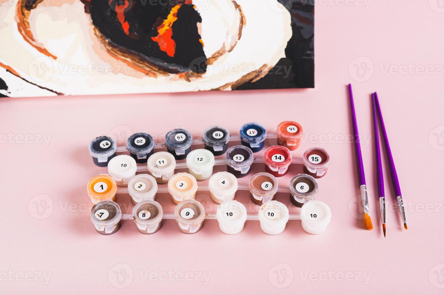 Set of colorful acrylic paints, brushes and canvas for painting by numbers on the pink table photo