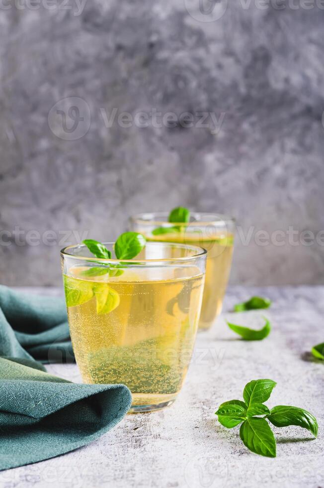 Organic basil lemonade in glasses and leaves on table vertical view photo