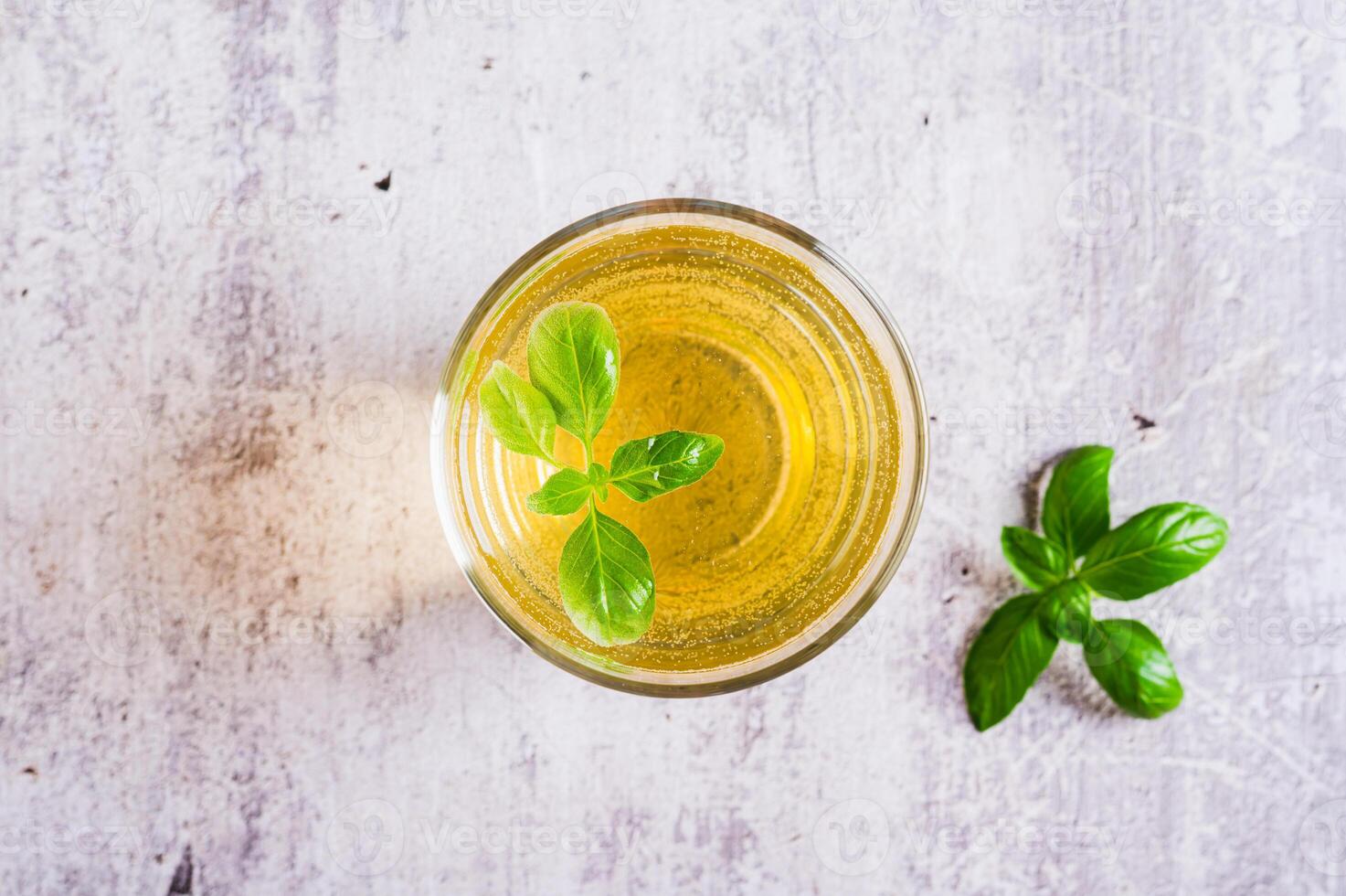 Close up of organic basil lemonade in a glass and leaves on table top view photo