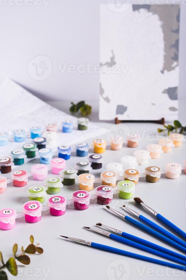 Painting by numbers kit, paints, brushes and paper on table vertical view photo
