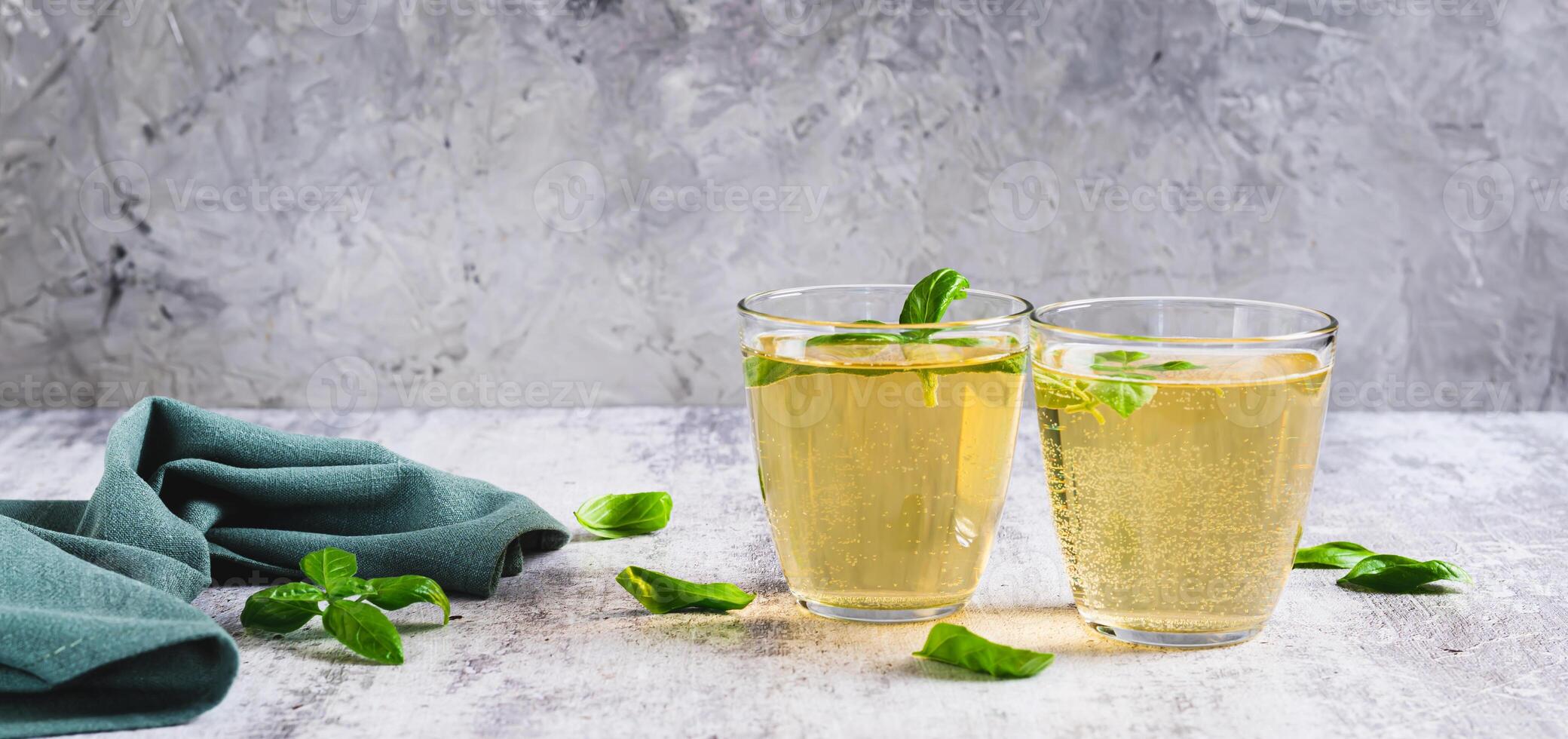 Organic basil lemonade in glasses and leaves on table web banner photo