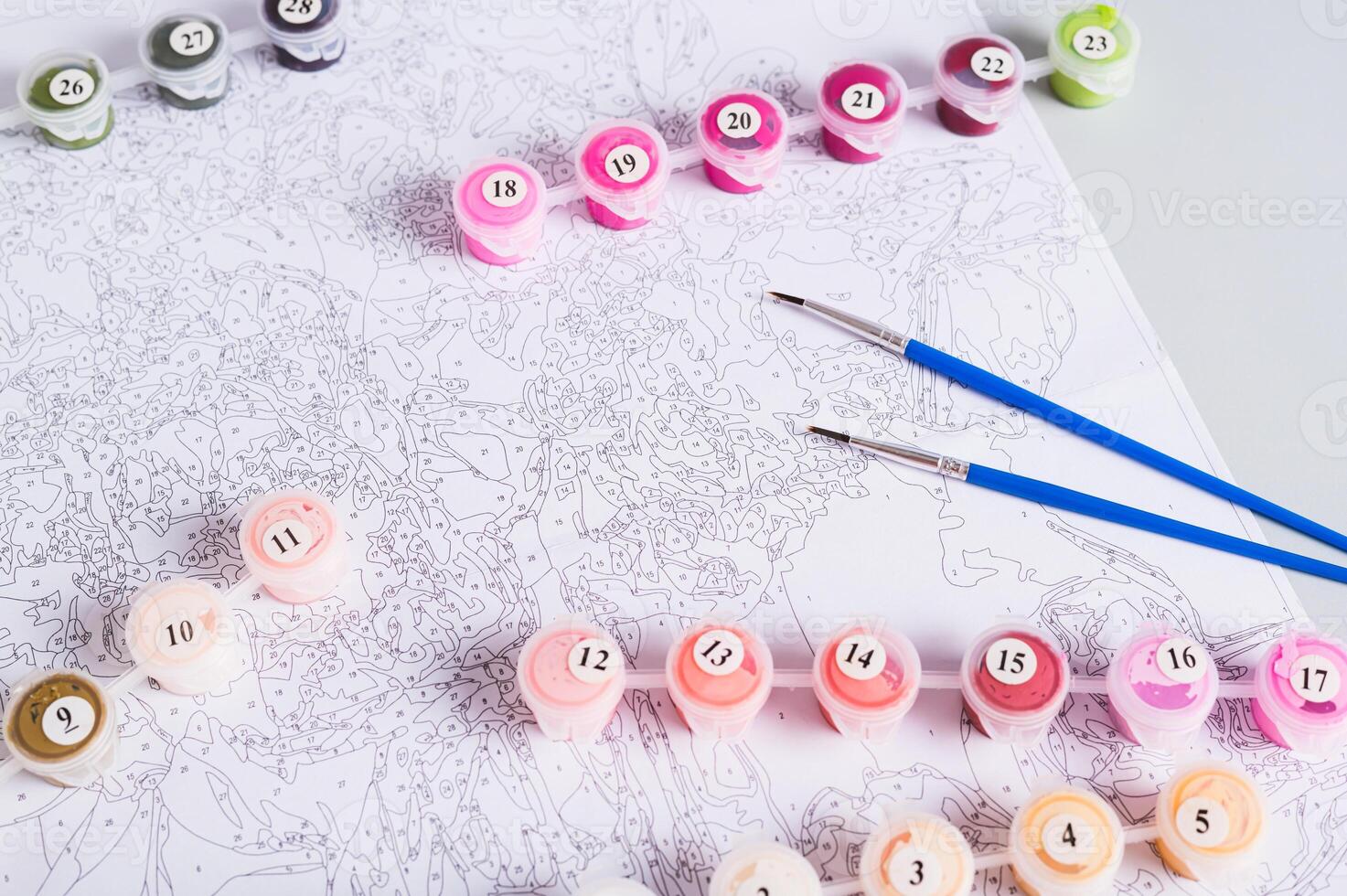 Paint containers, brushes and a paint by numbers chart on a table photo