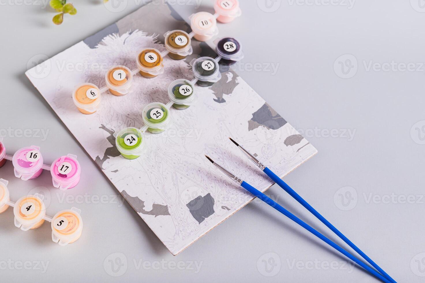Painting by numbers, paints and brushes on table for leisure photo