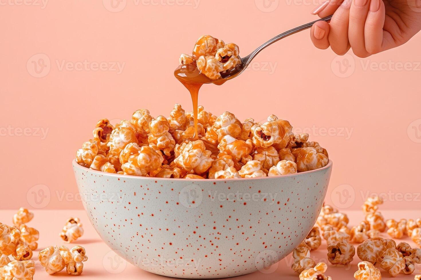 Delicious caramel popcorn in a bowl with a hand using a spoon to serve the treat photo