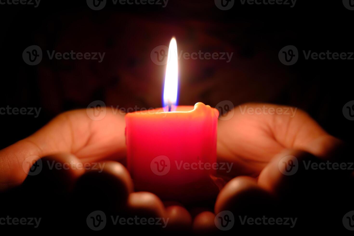A beautiful Red Candle Glowing gently in the Dark Hands of those who seek comfort and warmth photo