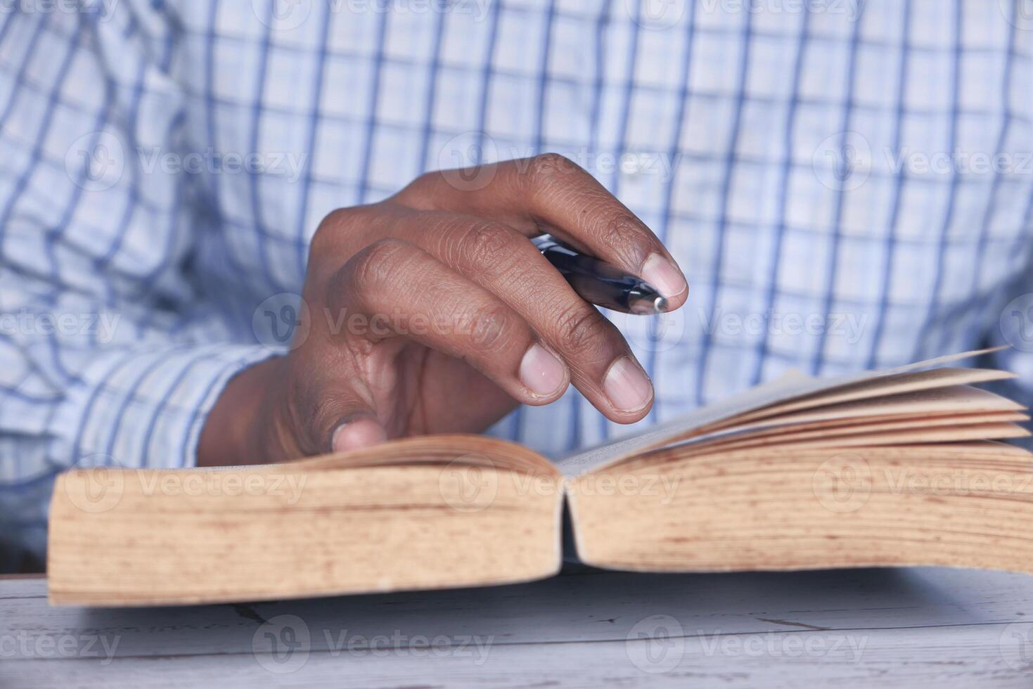 A focused individual is taking detailed notes while deeply reading an engaging book photo