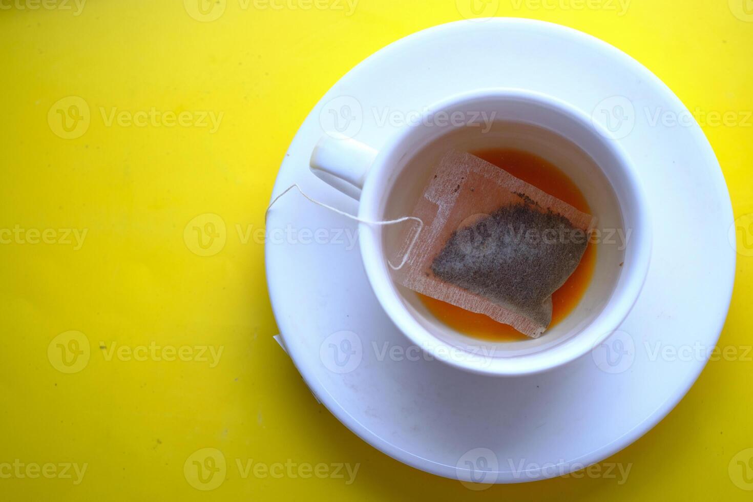 A lovely cup of tea brews on a bright yellow surface, creating an inviting atmosphere photo