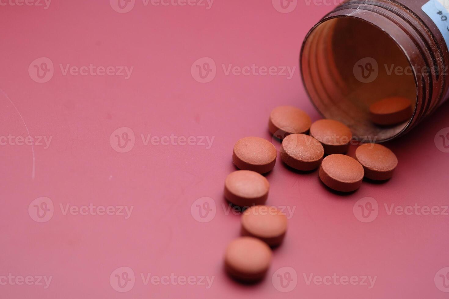 A Collection of Scattered Tablets from a Medicine Bottle Spread across a Soft Pink Background photo
