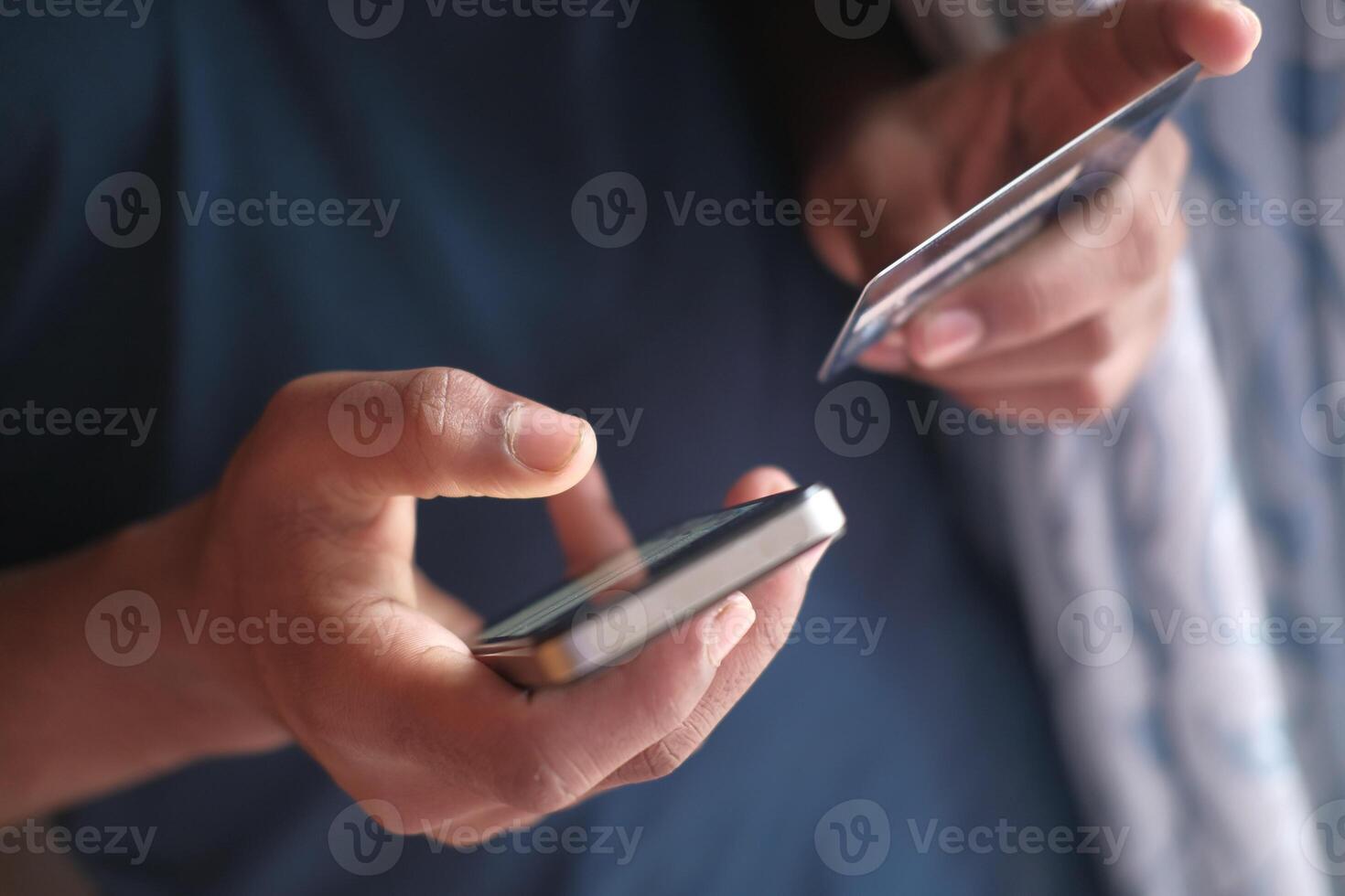 A person is using a smartphone along with a credit card to facilitate an online payment transaction photo