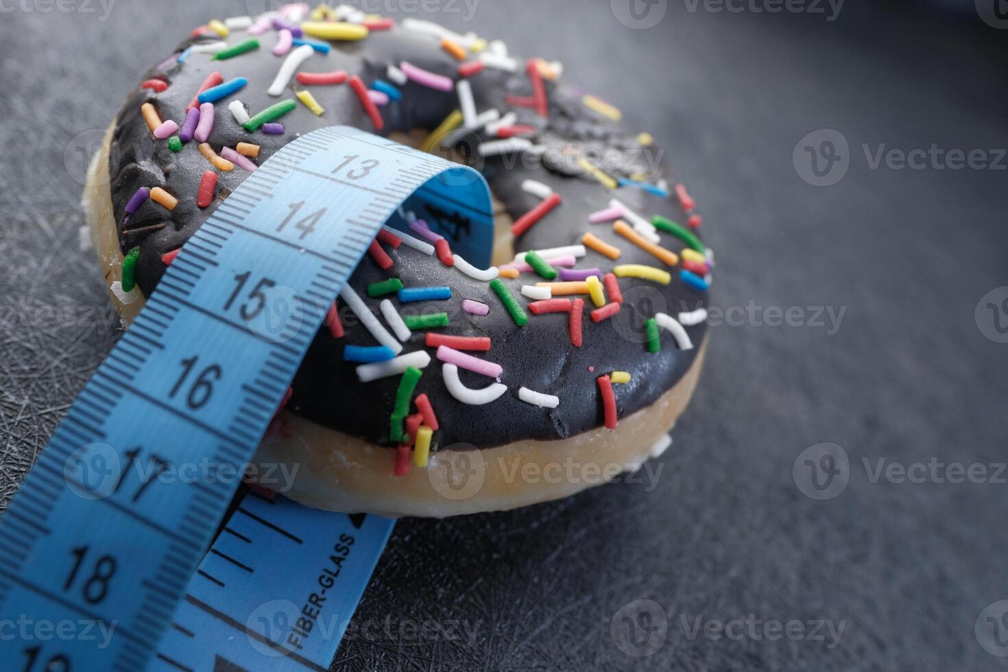 A delightful Chocolate Donut topped with colorful Sprinkles alongside a Measuring Tape photo