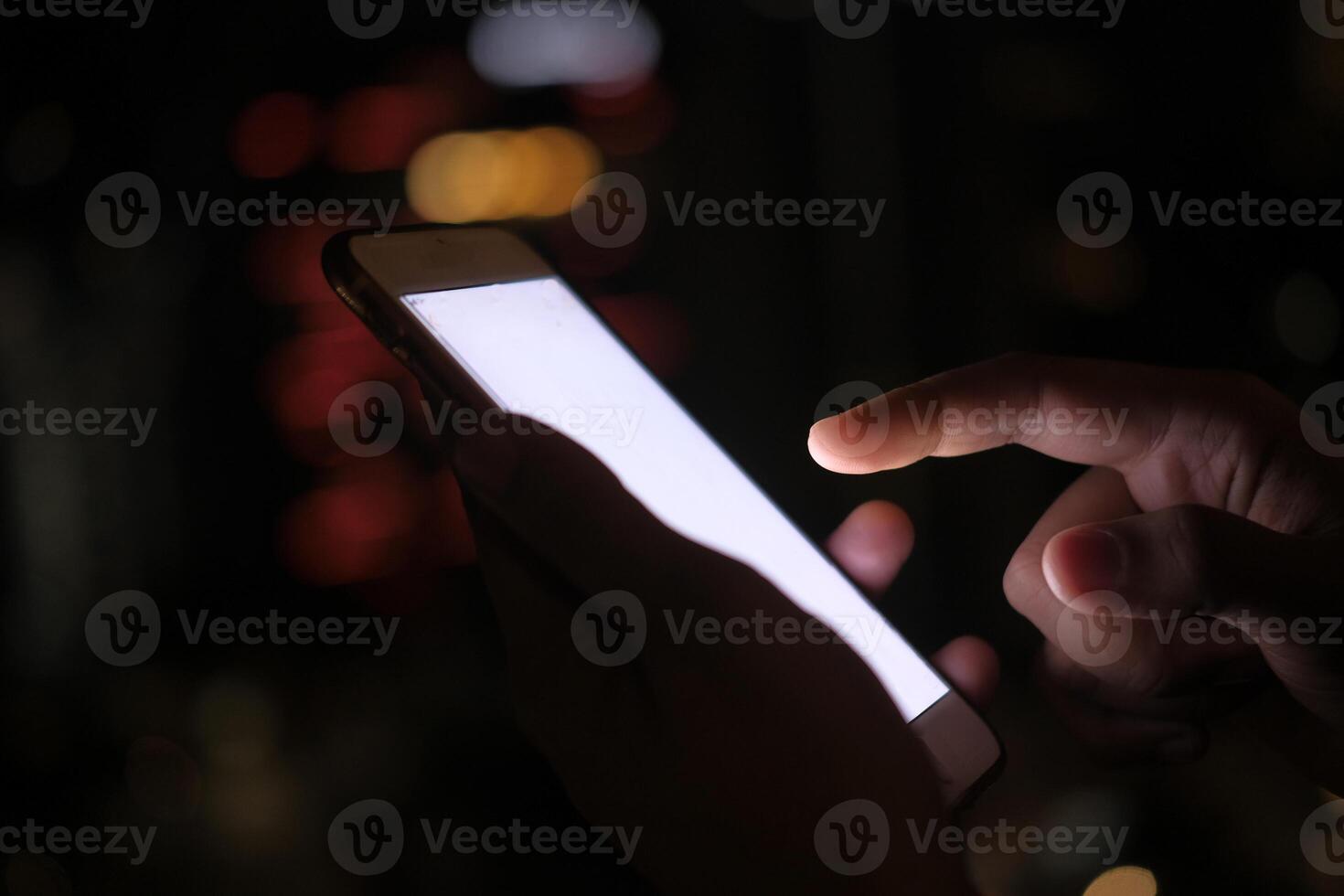 An individual is utilizing a smartphone in an environment characterized by dim lighting conditions photo