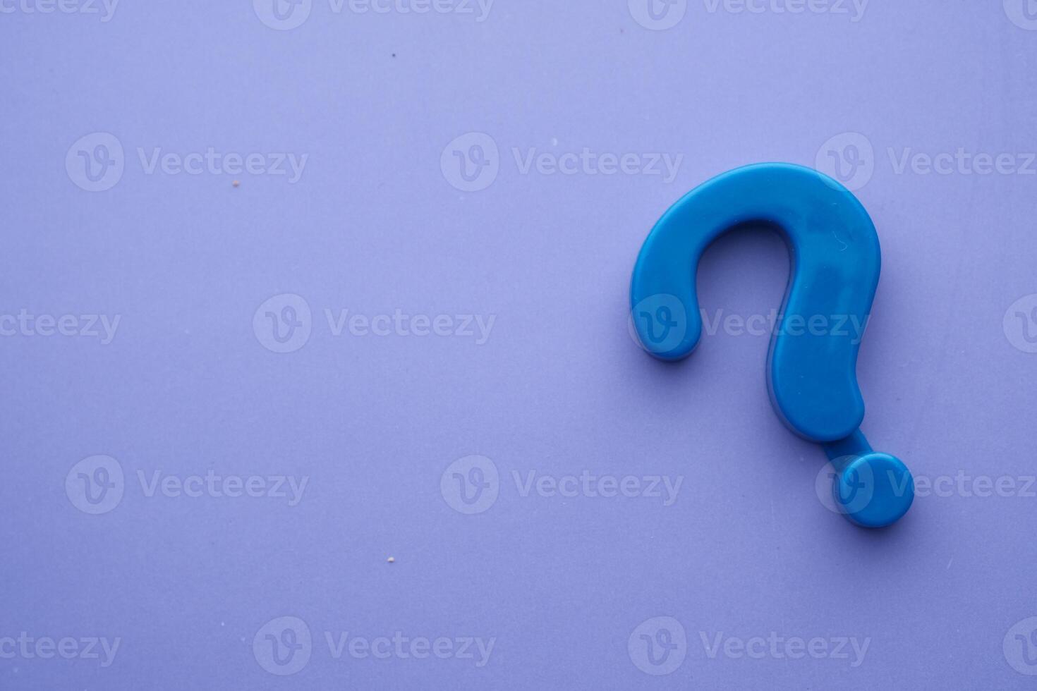 A Blue Plastic Question Mark Symbol Set Against a Light Purple Background, Creating Visual Interest photo
