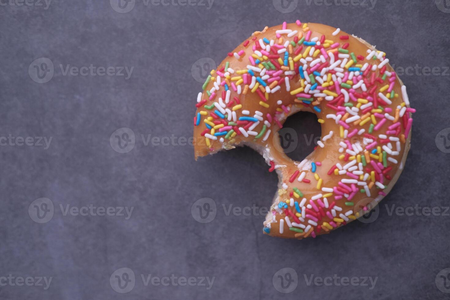 A Colorful Sprinkled Donut with a Bite Taken Out, Truly Perfect for Any Sweet Tooth Craving photo