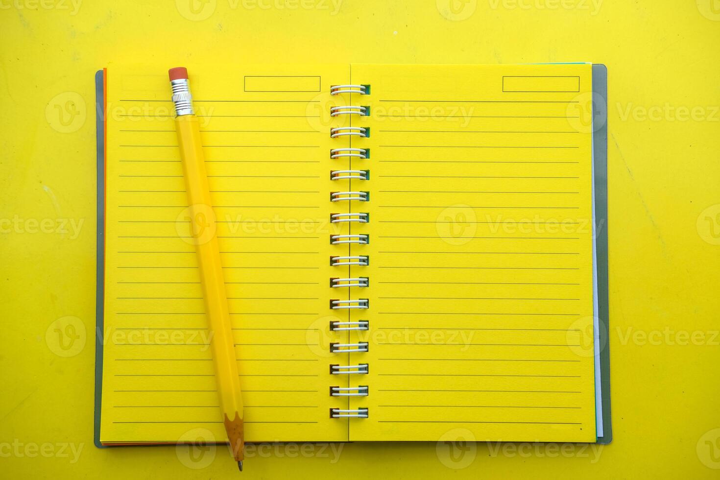 A Yellow Notepad with a Pencil on a Vibrant Yellow Background creates a lively scene photo