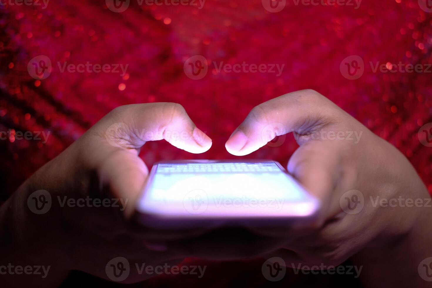 A Person Engaged with Their Mobile Phone in Low Lighting with an Enchanting Festive Background photo
