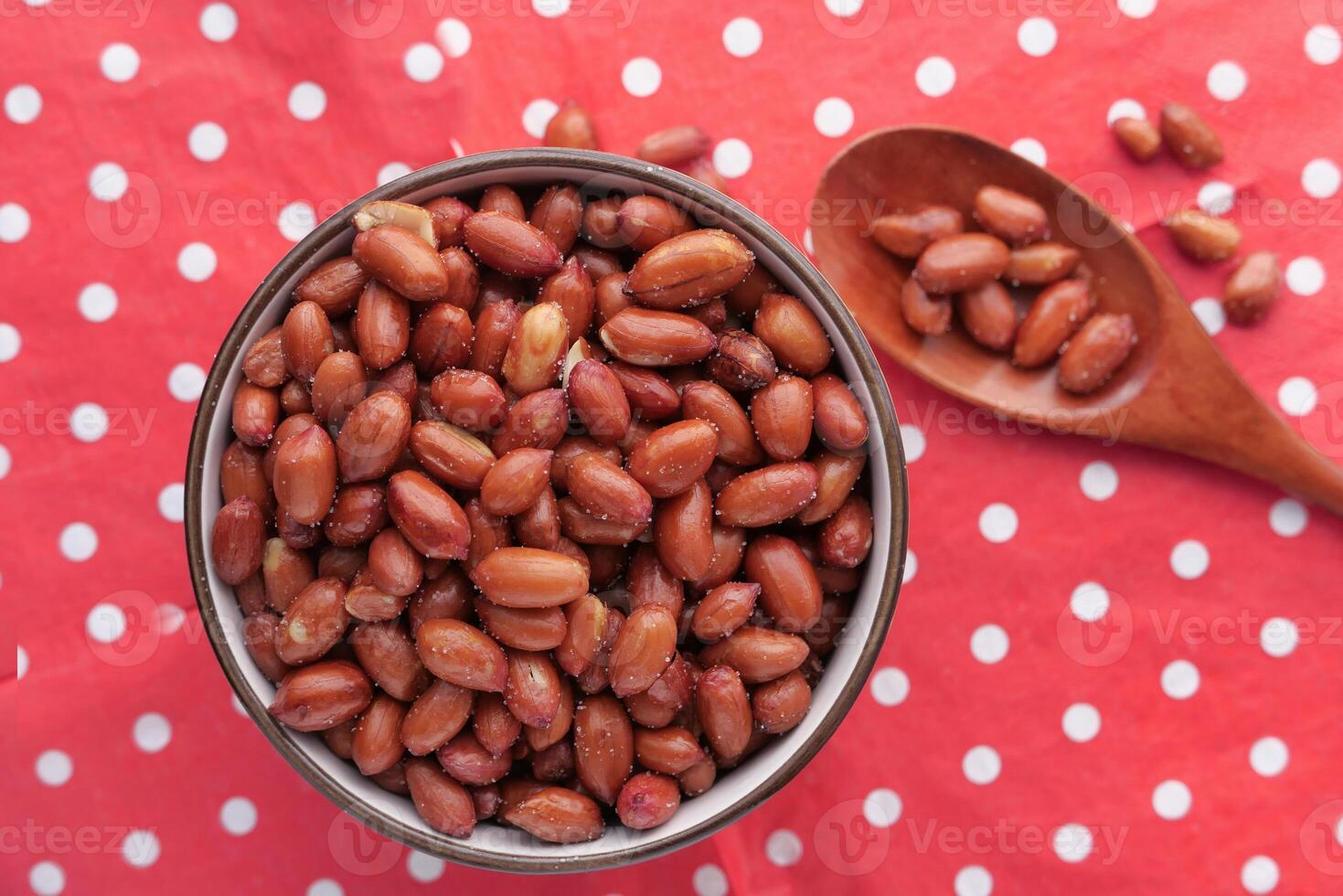 A Bowl Filled with Healthy Red Peanuts Set Against a Colorful Polka Dot Background photo