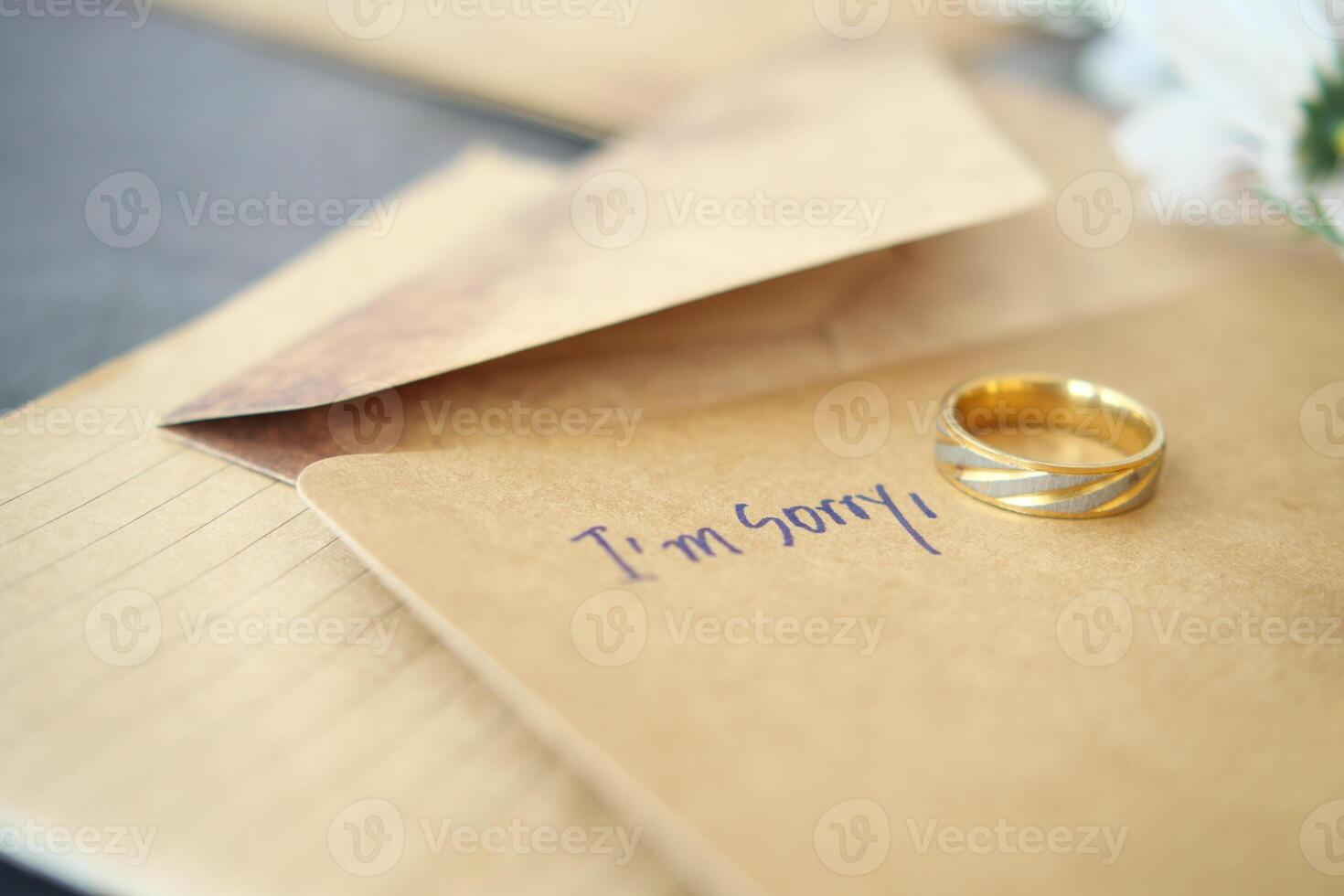 Note with the sorry word next to a wedding ring. photo