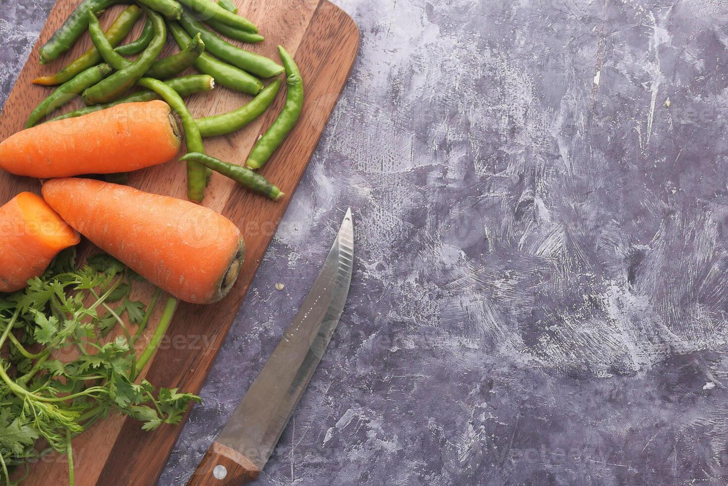 Fresh vegetables artfully displayed on a wooden cutting board with a knife for prep photo