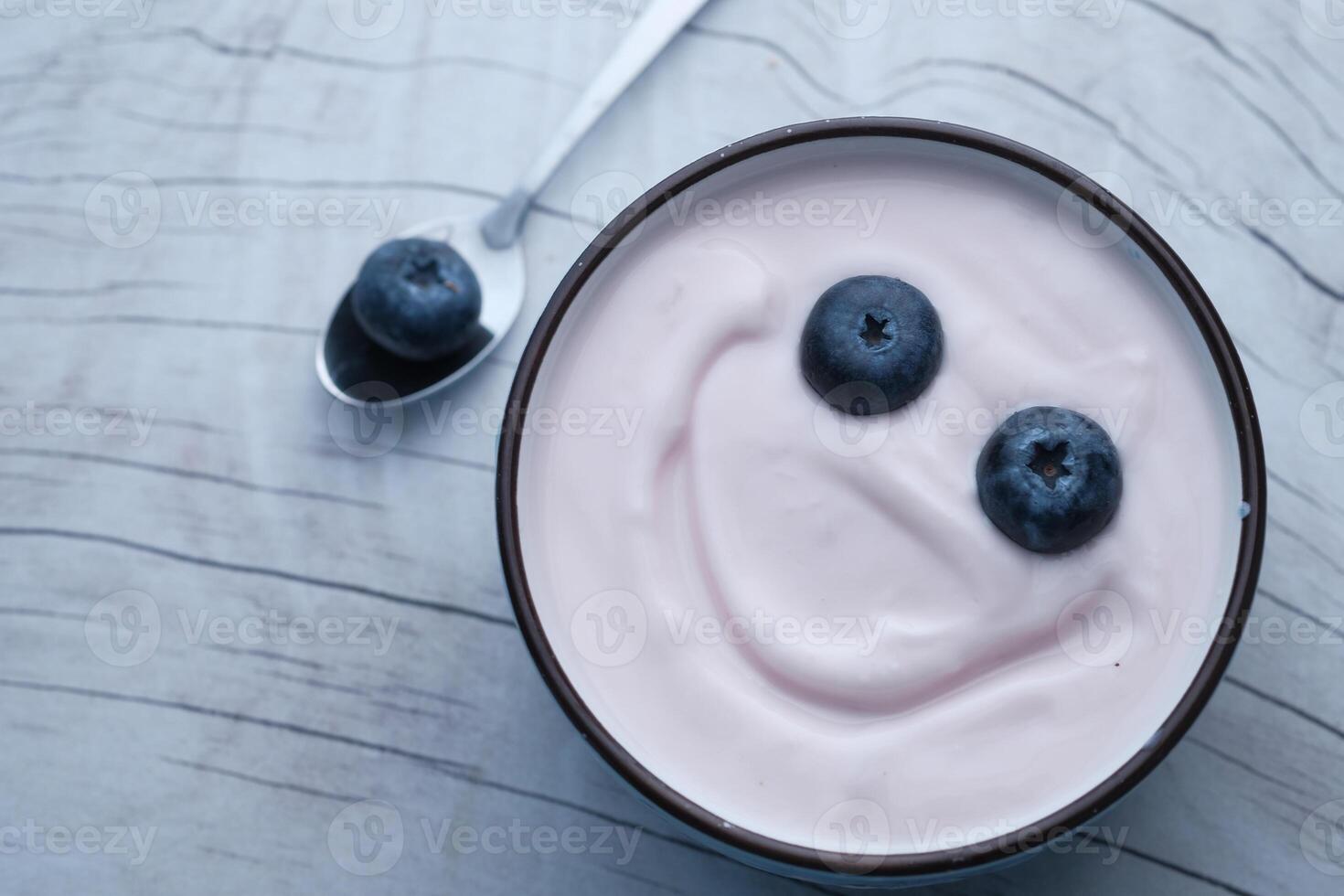 A delightful and playful yogurt bowl topped with fresh blueberries and a cheerful smiley face photo