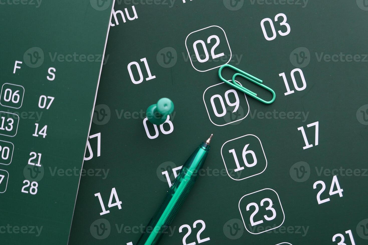 A calendar with a pen and paperclip on a dark surface creates an intriguing aesthetic photo