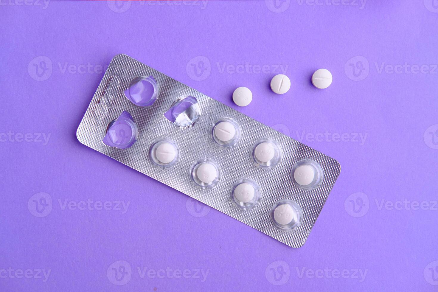 A Blister Pack Containing White Pills Set Against a Purple Background for Visual Impact photo