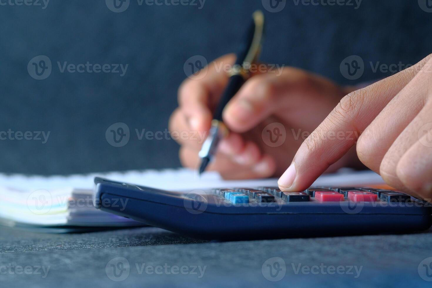 Hands Using a Calculator and Writing Notes on a Sheet of Paper for Better Understanding photo