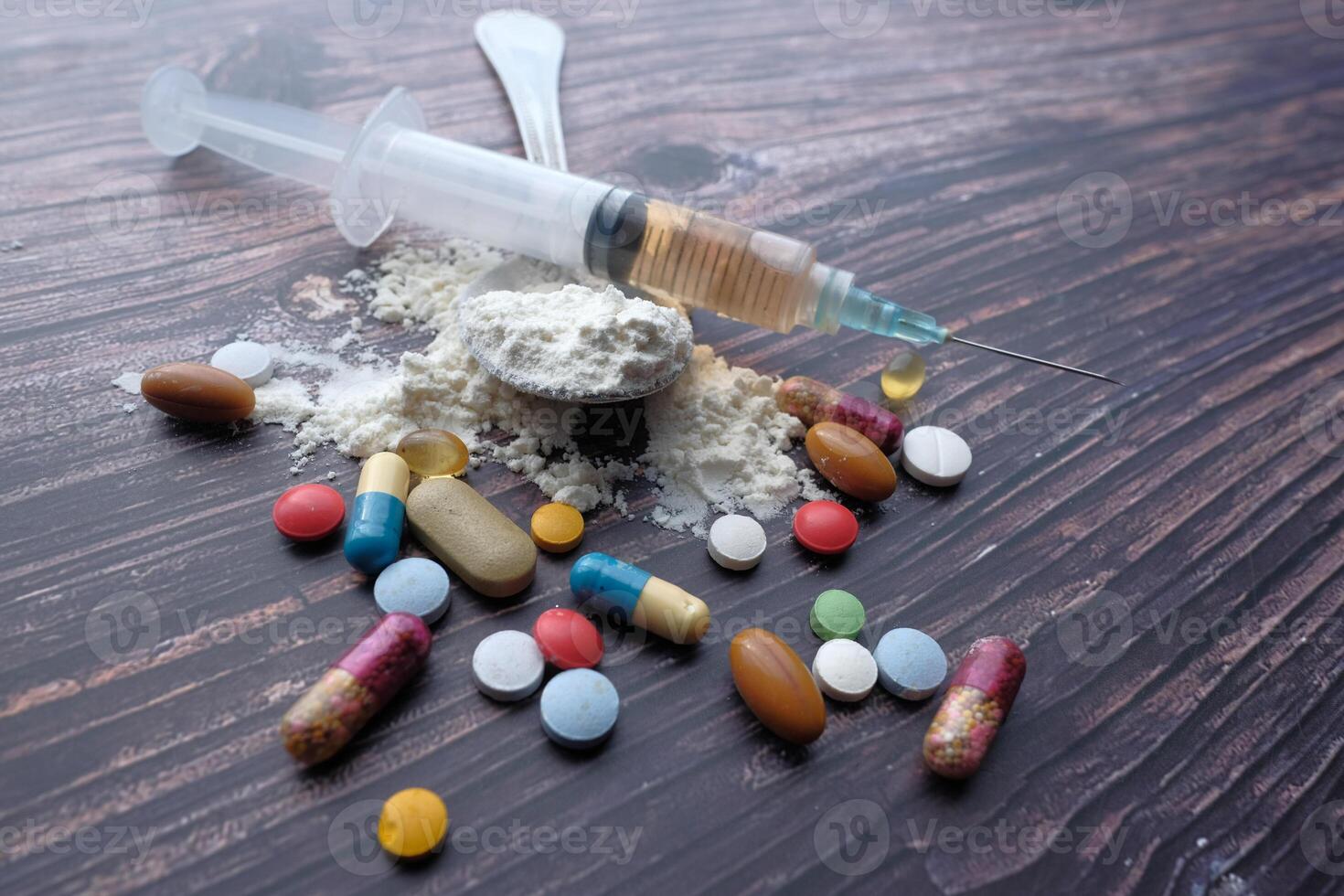 An Array of Diverse Assorted Drugs Along with a Syringe Set Against a Wooden Surface Background photo