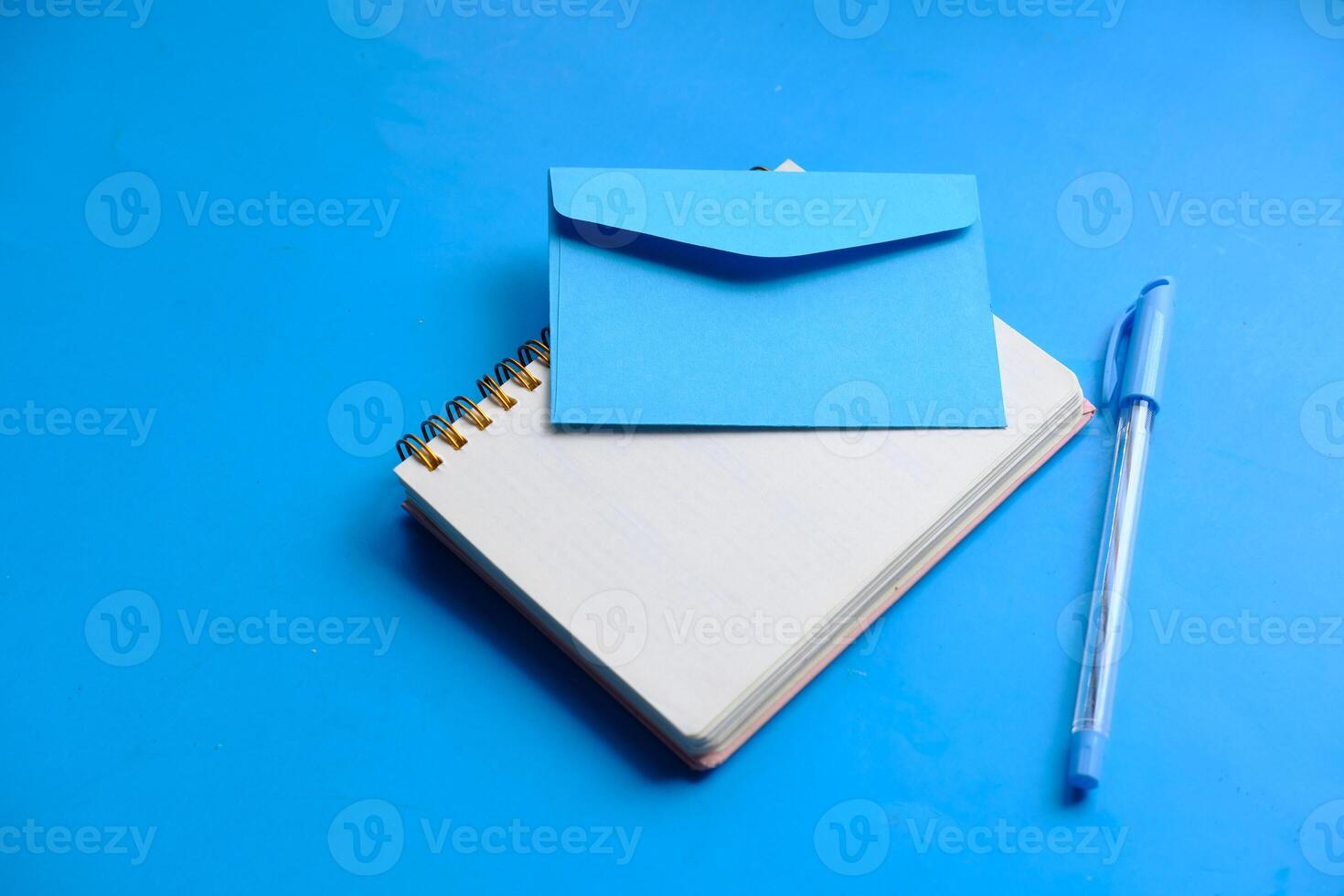 Aesthetic stationery setup on a blue background with a notebook and envelope for creativity photo