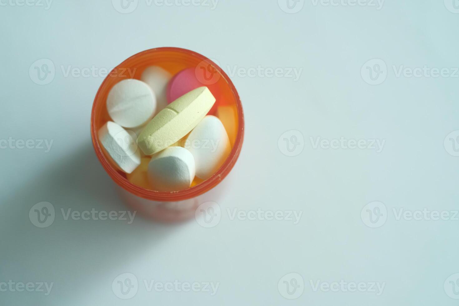 An assortment of colorful pills organized neatly in an orange container on a light background photo