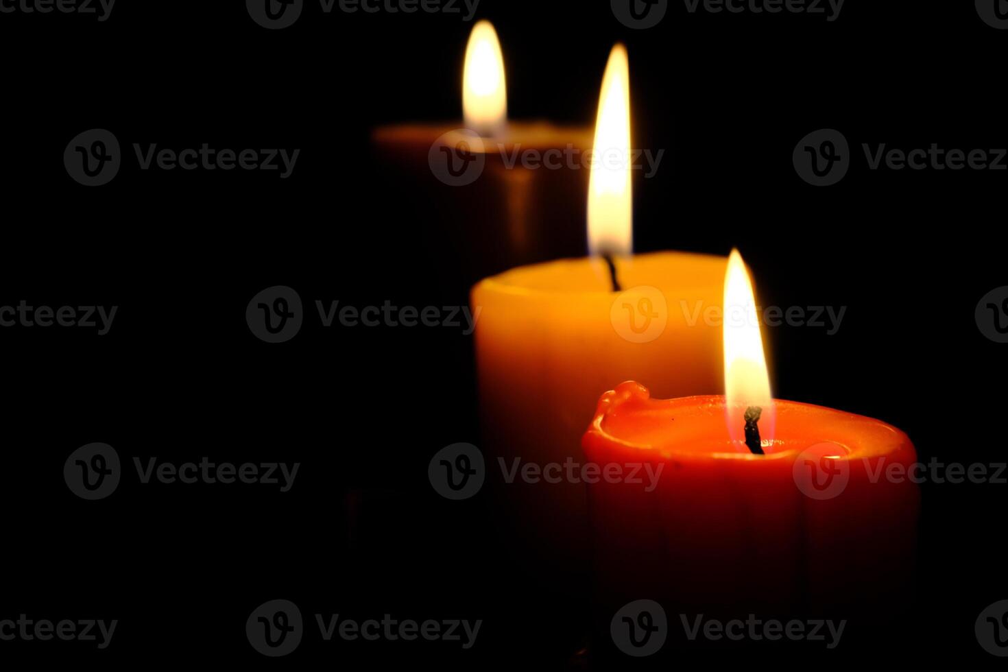 A beautiful trio of colorful, burning candles creates a stunning ambiance in the darkness photo