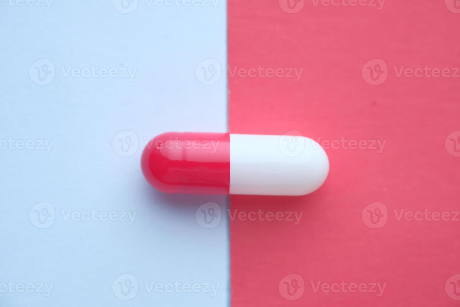 A Red and White Capsule Resting on a Vibrantly Colorful Background Displays its Appeal photo