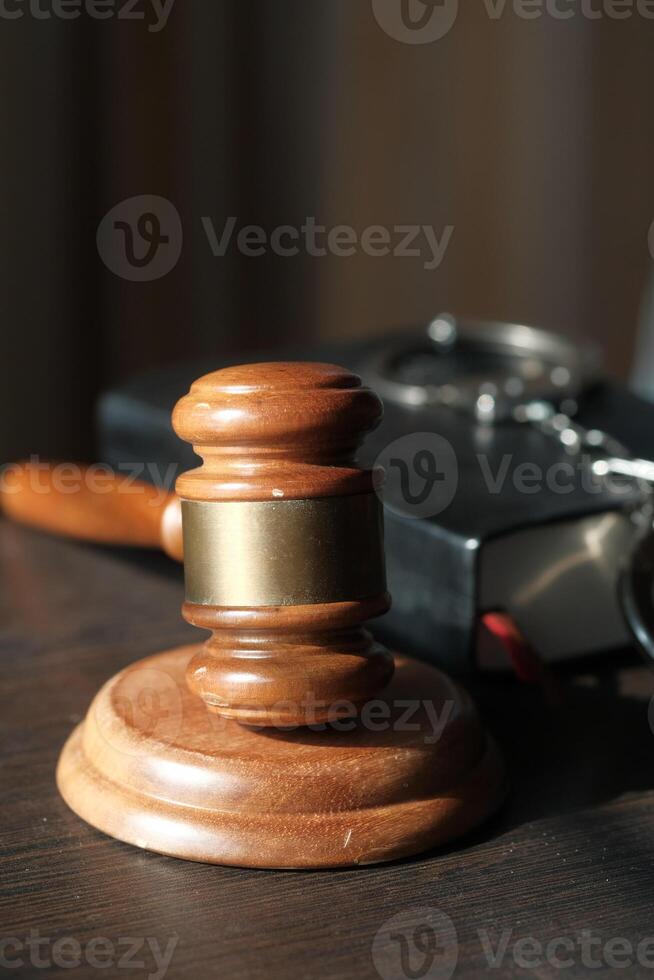 A traditional Wooden Gavel resting on a Table alongside a Law Book and various Legal Tools photo