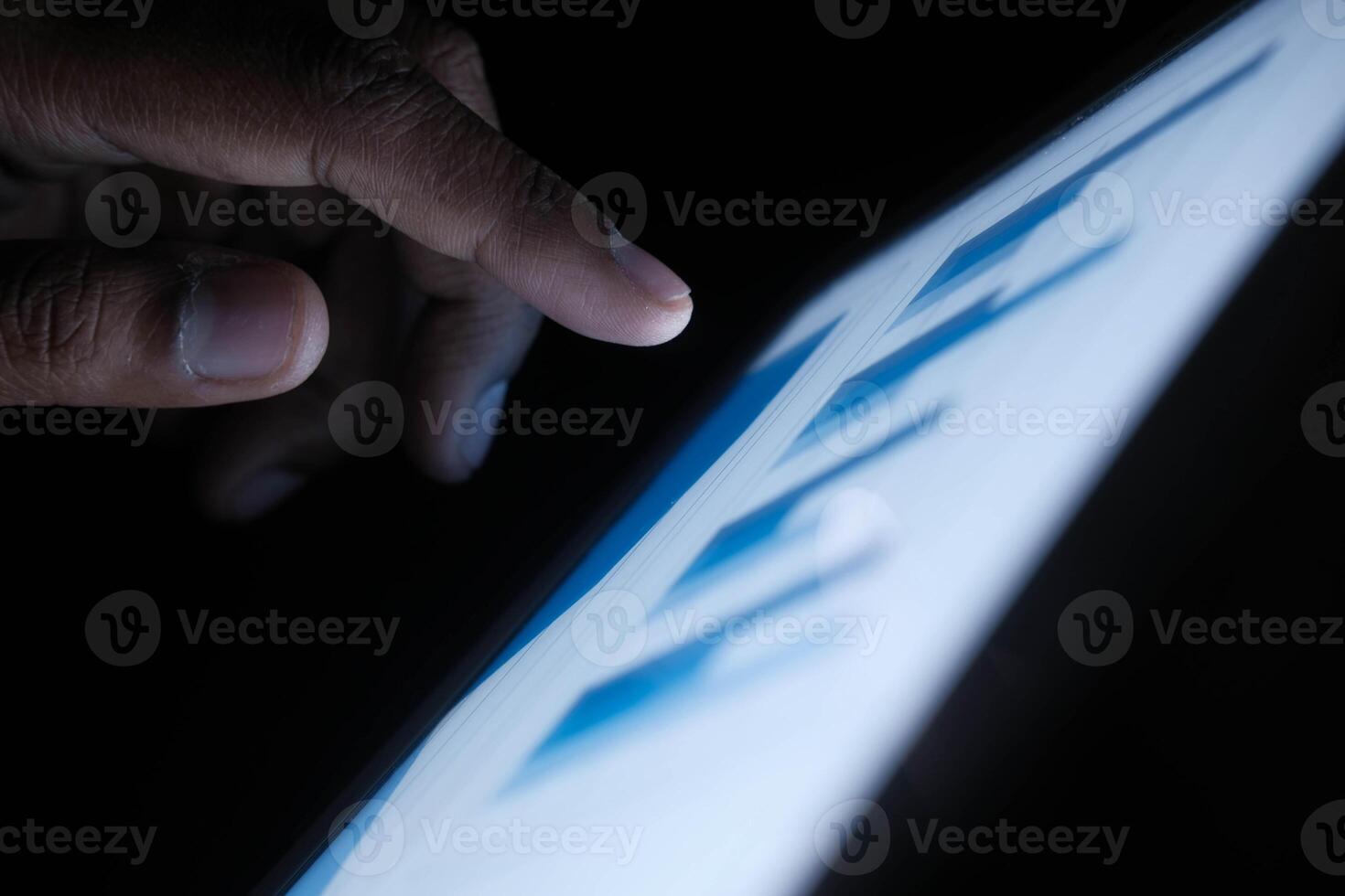 A person is interacting with a tablet screen in a low light environment, utilizing touch photo