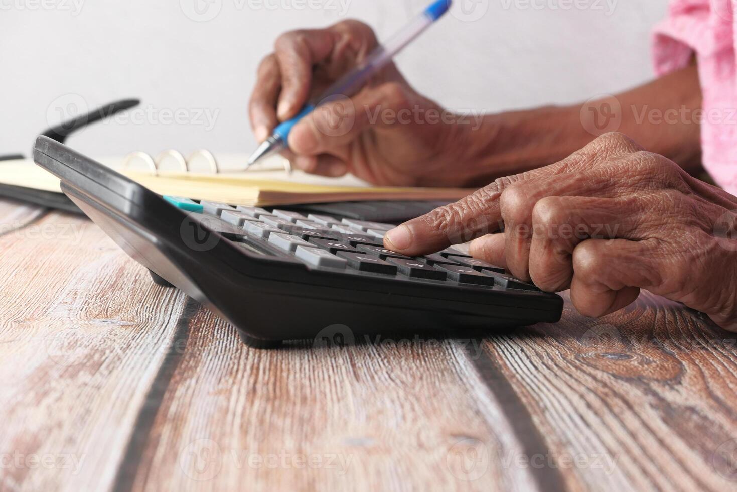 A Person Using a Calculator and a Notepad for Detailed Financial Calculation and Analysis photo