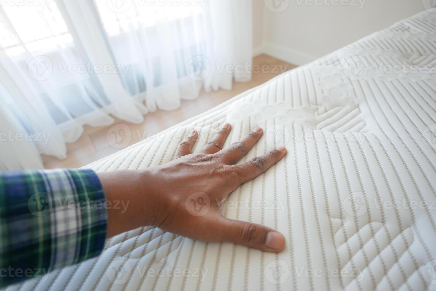 Hand touching and pressing orthopedic mattress on bed. photo