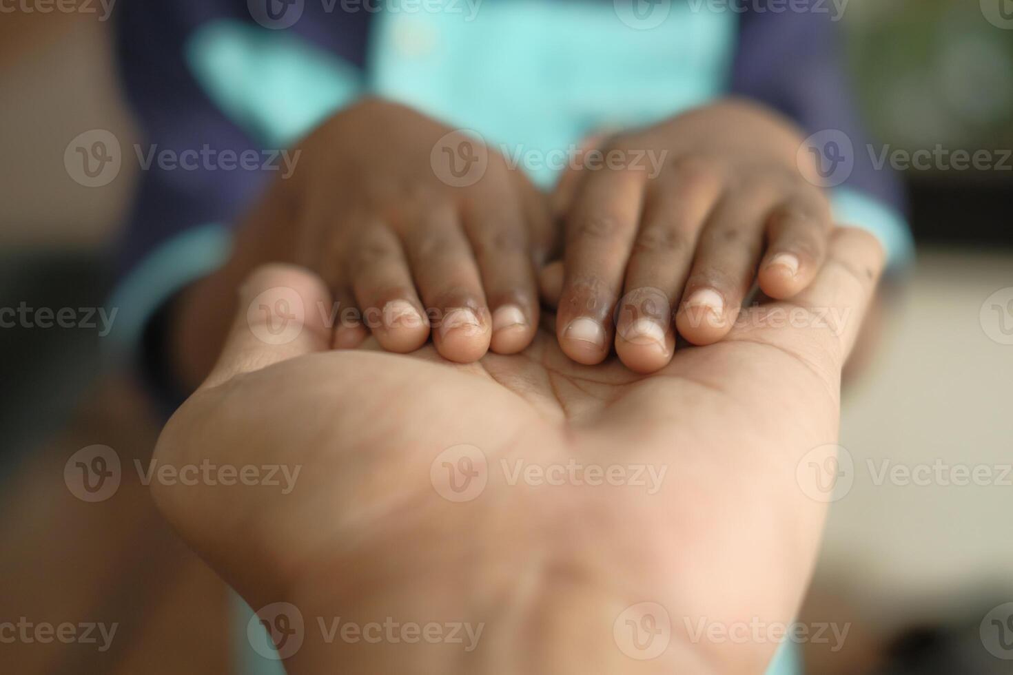 A childs small hands are resting gently and lovingly on the larger hand of an adult photo