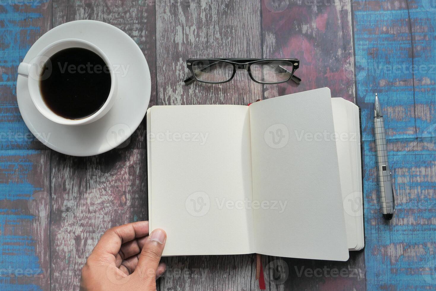 A creatively designed workspace featuring a cup of coffee, stylish glasses, and an open notebook photo