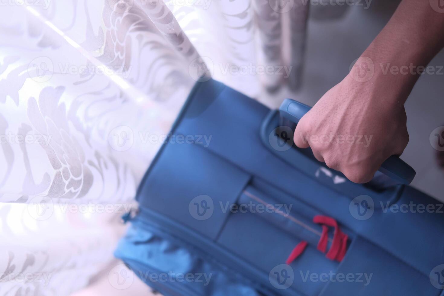 A hand holds a blue bag as soft light streams through a curtain, creating contrast photo