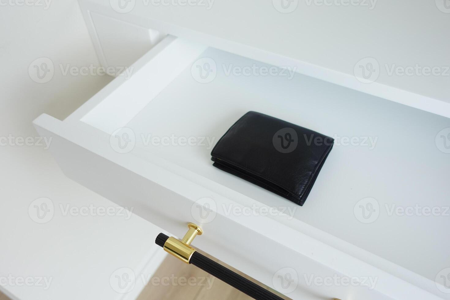 A minimalist black wallet on a white drawer, showcasing a stylish contemporary design photo