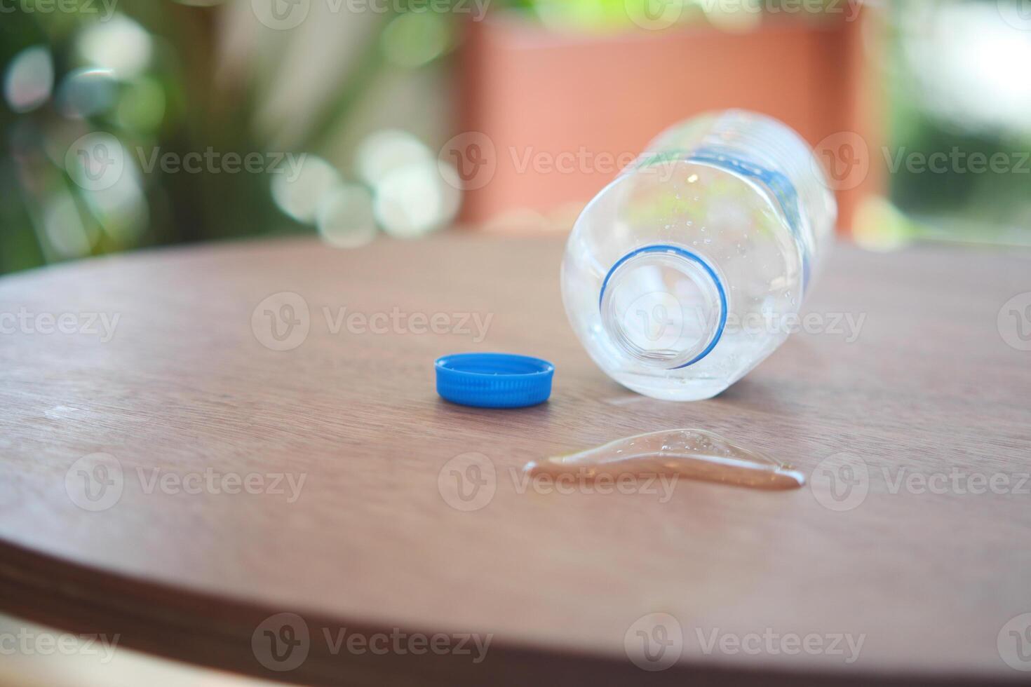A Water Bottle and Its Cap Have Been Accidentally Spilled All Over the Table Surface photo