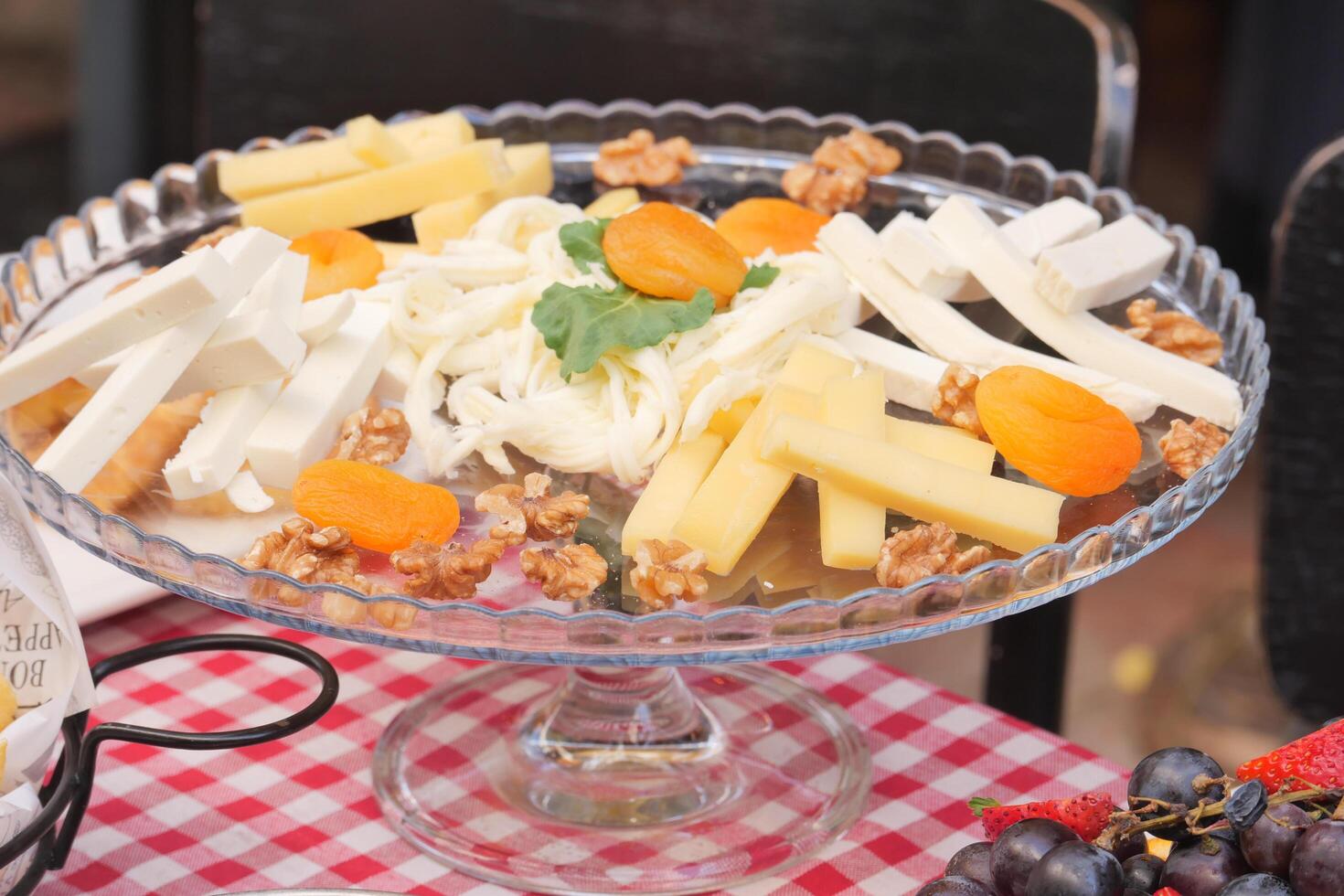 A beautifully arranged fruit and nut dessert display elegantly sitting on a glass stand photo