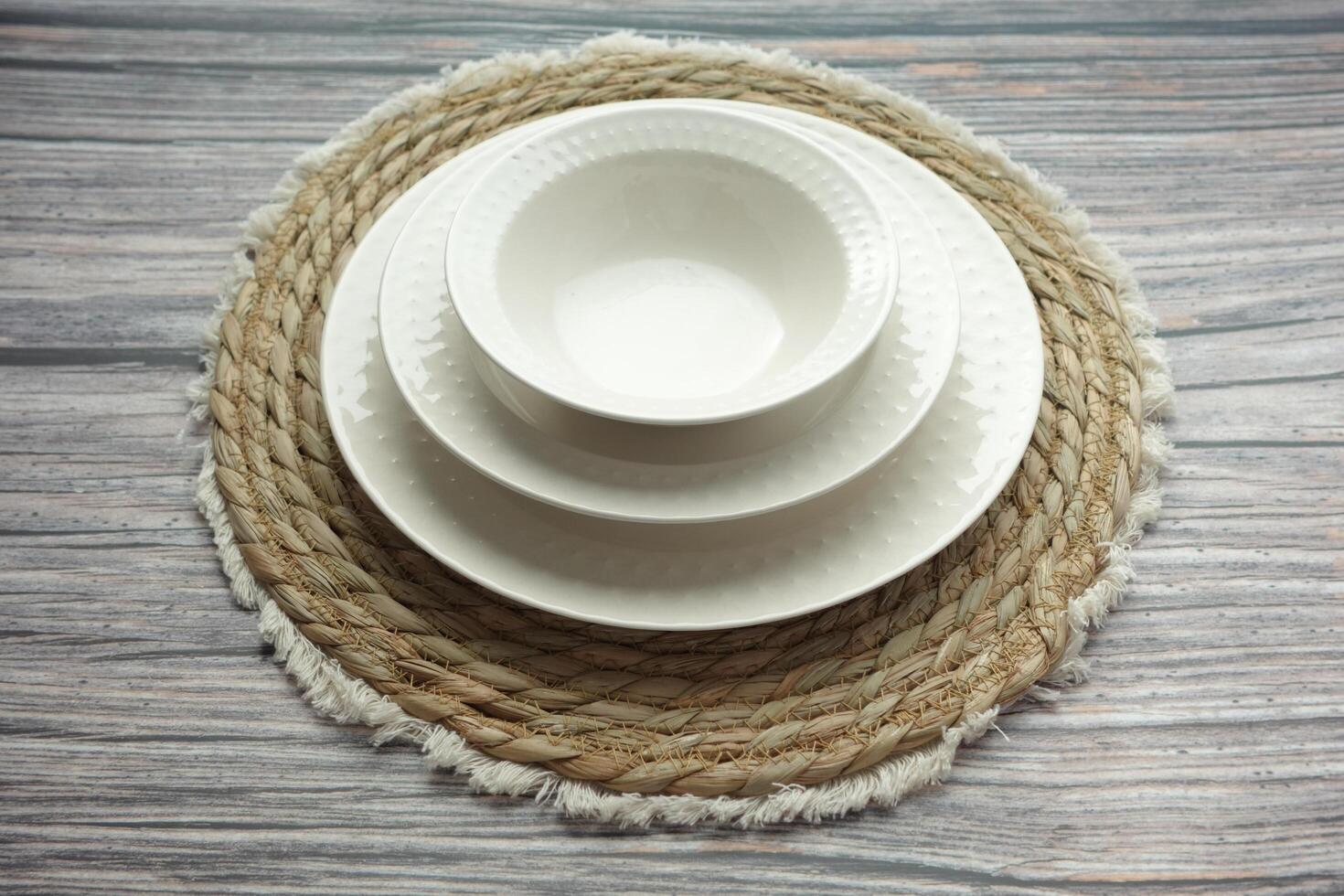 An Elegant White Dinnerware Set Displayed Beautifully on a Rustic Table Mat for Dining photo