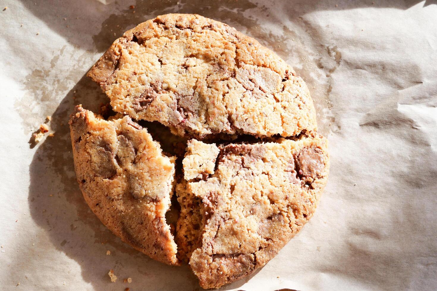 Deliciously Cracked Chocolate Chip Cookie Resting on a Sheet of Baking Paper for Your Delight photo