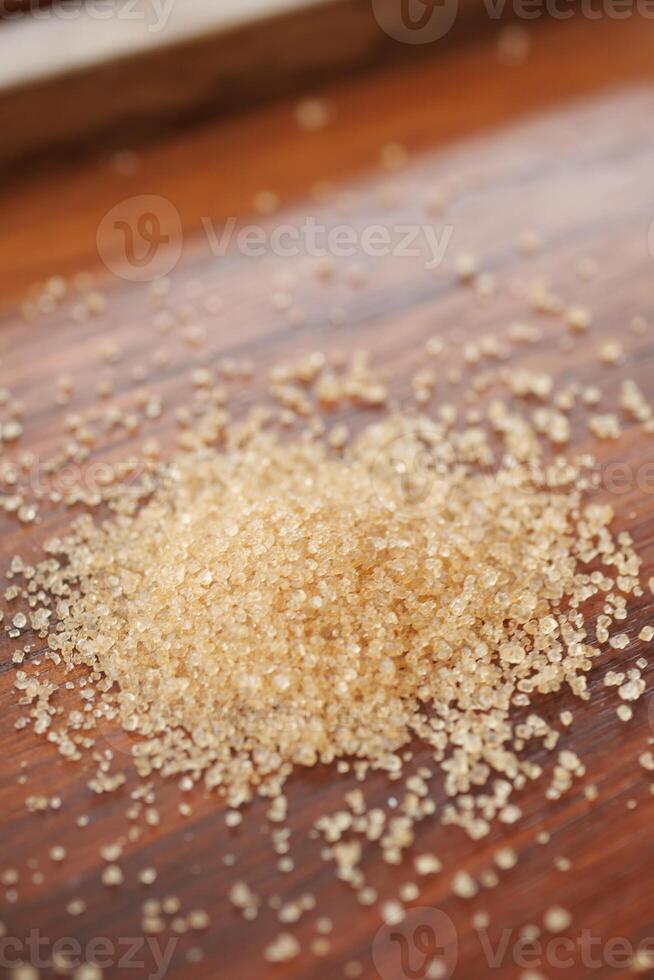 This image features a closeup view of a pile of brown sugar resting on a wooden surface photo