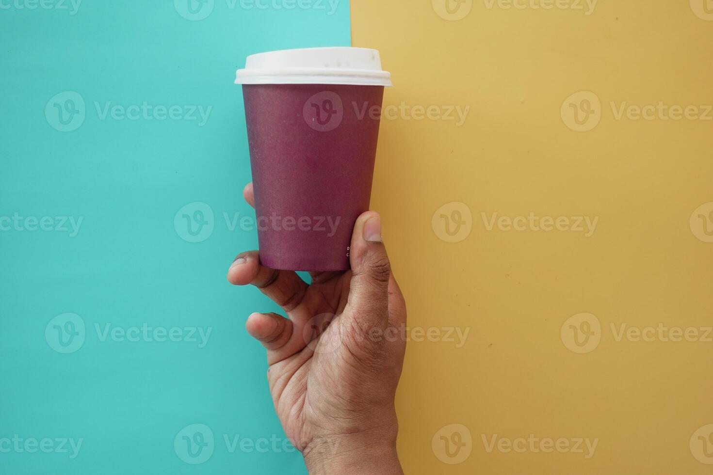 A hand elegantly holds a coffee cup against a vibrant, colorful background of various hues photo