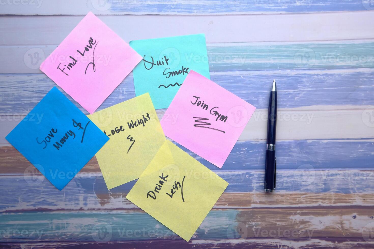 Colorful Sticky Notes with Handwritten Messages and a Pen on a polished Wooden Desk photo